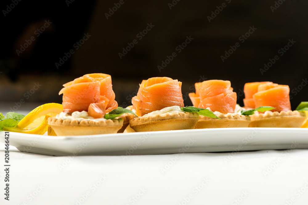 The salted smoked salmon in the basket is made in the form of a rose on a white plate The salted smoked salmon in the basket is made in the form of a rose on a white plate