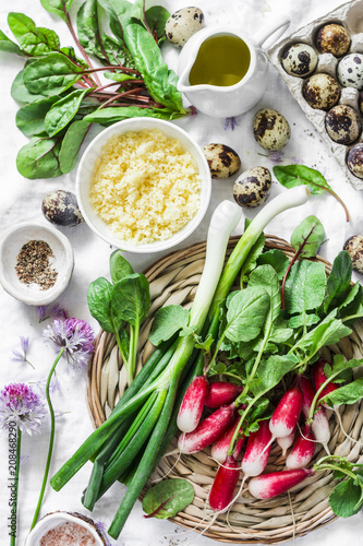 Healthy food ingredients - fresh spinach, chard, radish, couscous, quail eggs, olive oil on a light background, top view. Salad ingredients