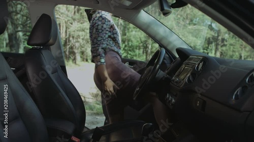 Elegant pretty long blonde hair woman in stylish outfit and eyeglasses fastening car seat belt and adjusting rear-view mirror before driving. Cute female driver buckles up before going on road trip.