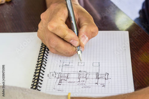 the Builder makes a sketch drawing of the house. Hand with a pen draws