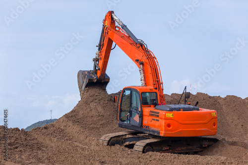 Earthworks Construction Operating Excavator Machine moving sand closeup photo.