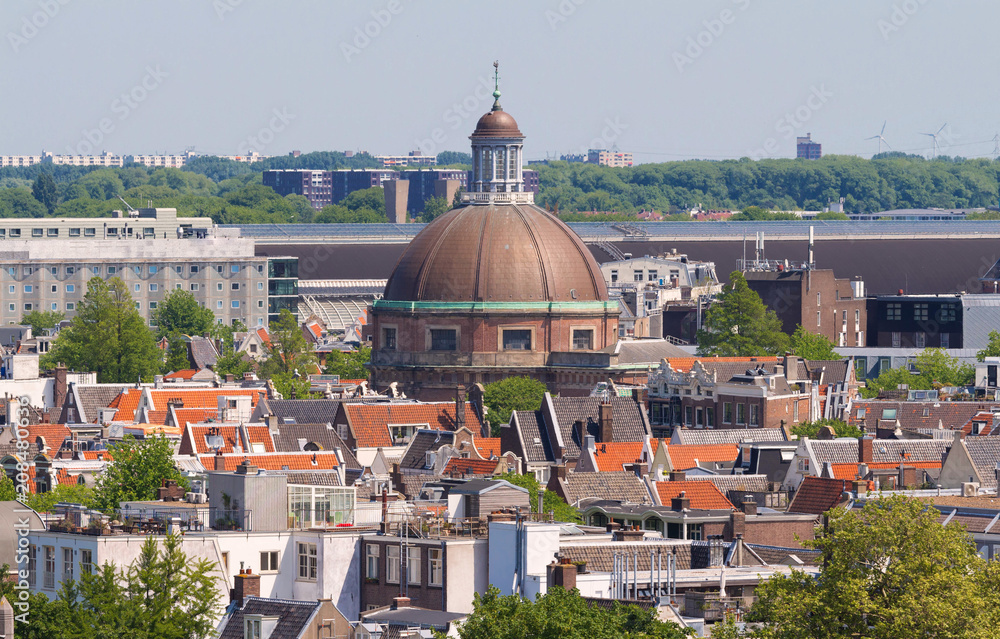 Round Koepelkerk with copper dome next to Singel canal . Roofs and facades of Amsterdam. City view from the bell tower of the church Westerkerk, Holland, Netherlands.