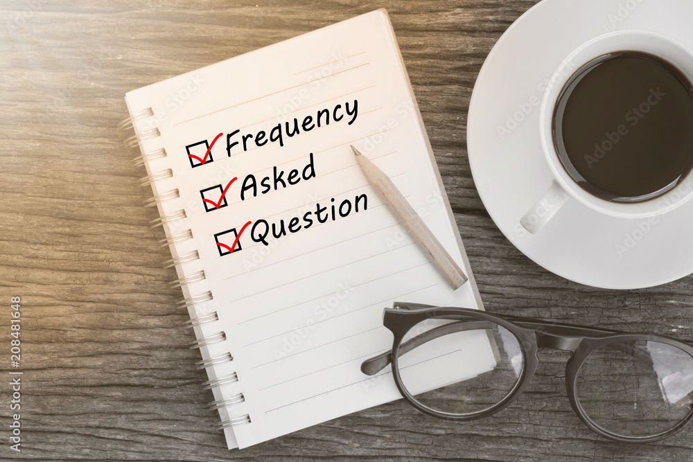Frequency Asked Question and check list marks in notebook with glasses, pencil and coffee cup on wooden table. FAQ concept.
