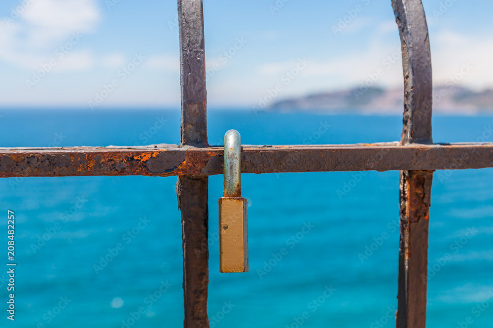 rusty padlock attached to a balustrade by the sea, a traditional way of showing love