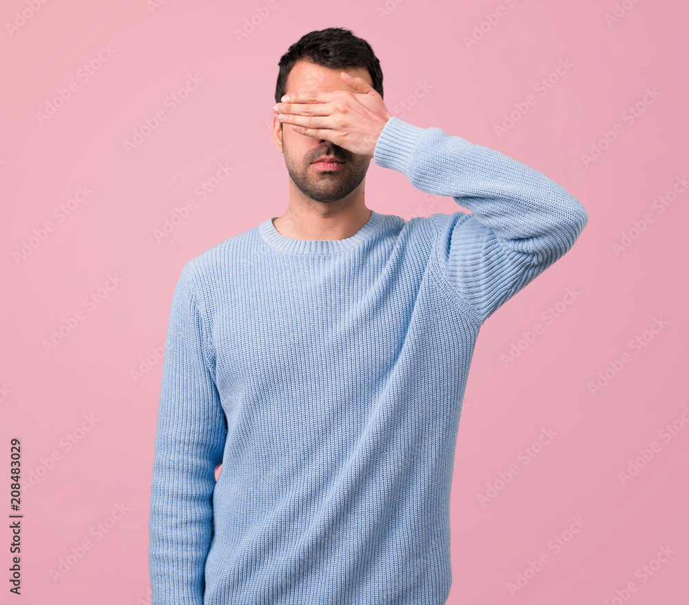 Handsome man covering eyes by hands on pink background Handsome man covering eyes by hands on pink background