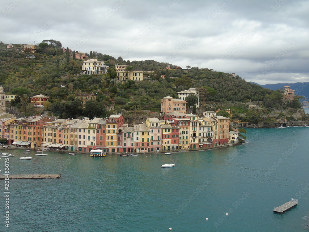 Walking around the seaside of Portofino  in Liguria with a grey sky, some green trees and some beautiful  waves