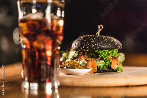 A delicious fresh black hamburger with Coca Cola on a bar counter
