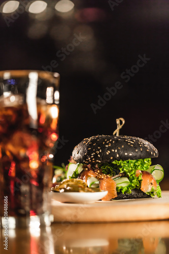 A delicious fresh black  hamburger with Coca Cola on a bar counter