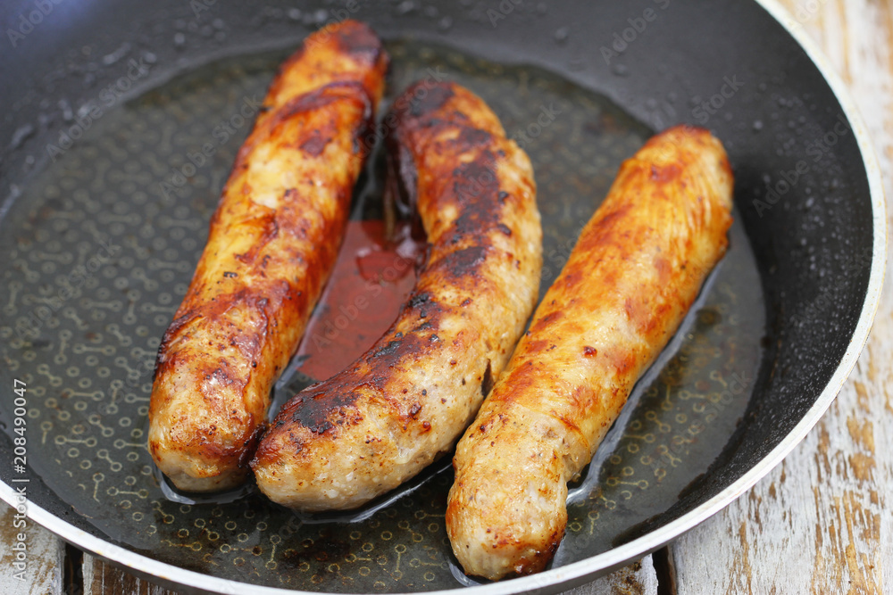 Three fried British pork sausages in frying pan
Three fried British pork sausages in frying pan