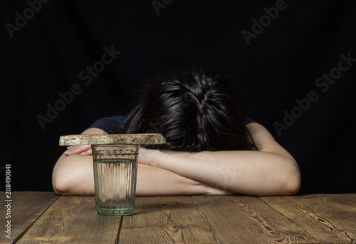 Canvastavla A glass of water and a piece of bread, the girl is lying on the table and lapach