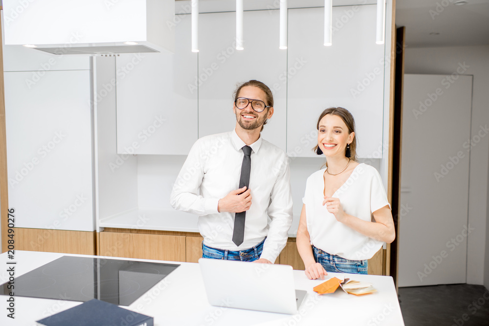 Young couple designing interior standing with laptop at the modern white kitchen