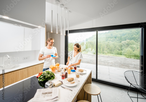Fotografie Young couple cooking breakfast with healthy food and coffee standing at the mode