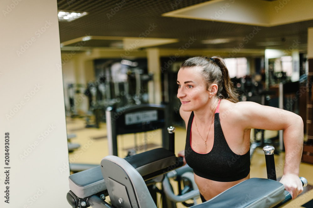 Young fitness woman hanging and performing working with abdominal muscles press on the horizontal bar in gym club. fitness, sport, training concept. Young fitness woman hanging and performing working with abdominal muscles press on the horizontal bar in gym club. fitness, sport, training concept.