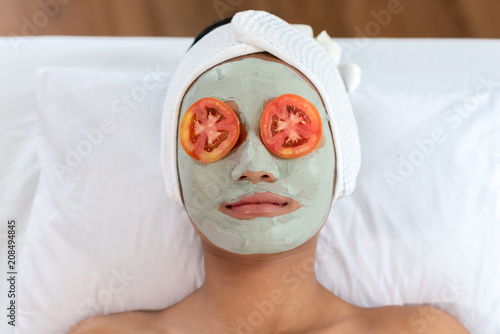  Young woman having clay facial mask in beauty salon