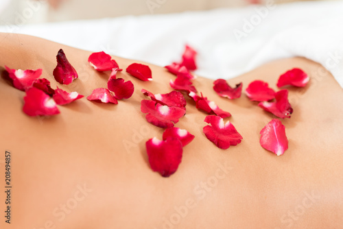 Young beautiful woman lying in bed covered by flower in spa massage