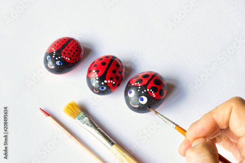 three painted stones as cute ladybugs on white background