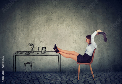 Frustrated business woman sitting at her desk mad with her unreliable laptop