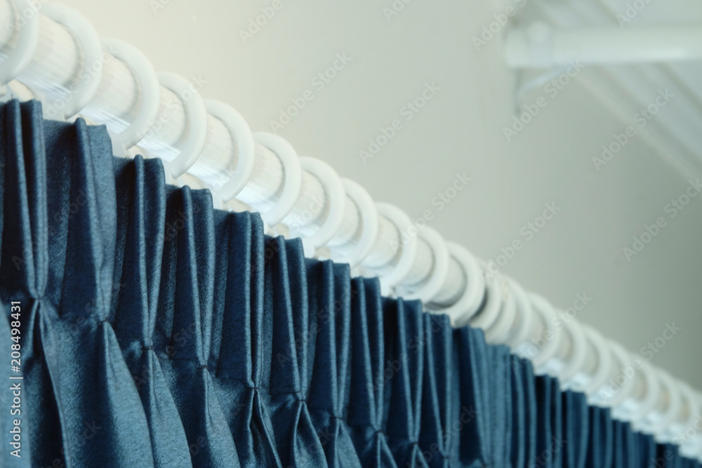 Blue curtain hanging on the round white rails