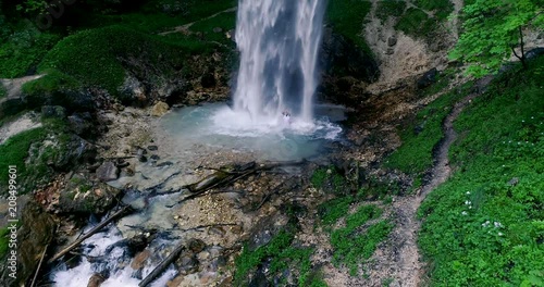 European man with beard is doing waterfall-meditation while standing under big waterfall in austria, wildensteiner waterfall photo