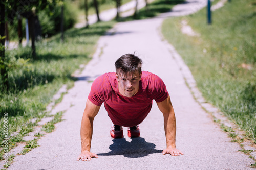 Young male fitness model doing push ups outdoor