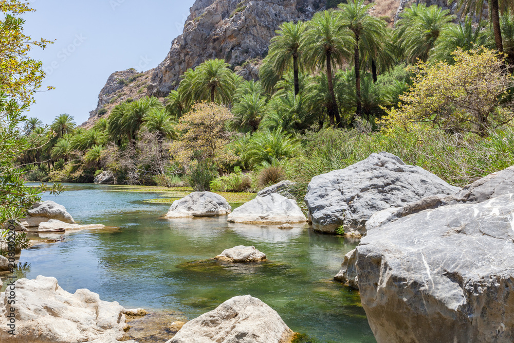 Wanderung durch die Preveli Schlucht auf Kreta Griechenland. Blick auf den Fluss mit Palmen, Wasser und Felsen