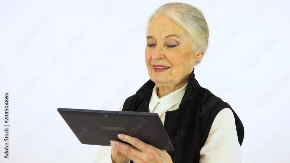An elderly woman works on a tablet with a smile - white screen studio An elderly woman works on a tablet with a smile - white screen studio