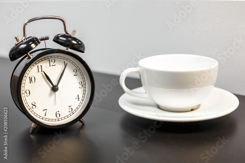alarm clock on the table and white mug, tea time, rest concept