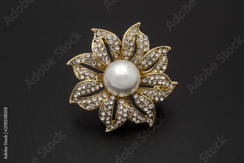 gold brooch flower with a pearl and diamonds isolated on black