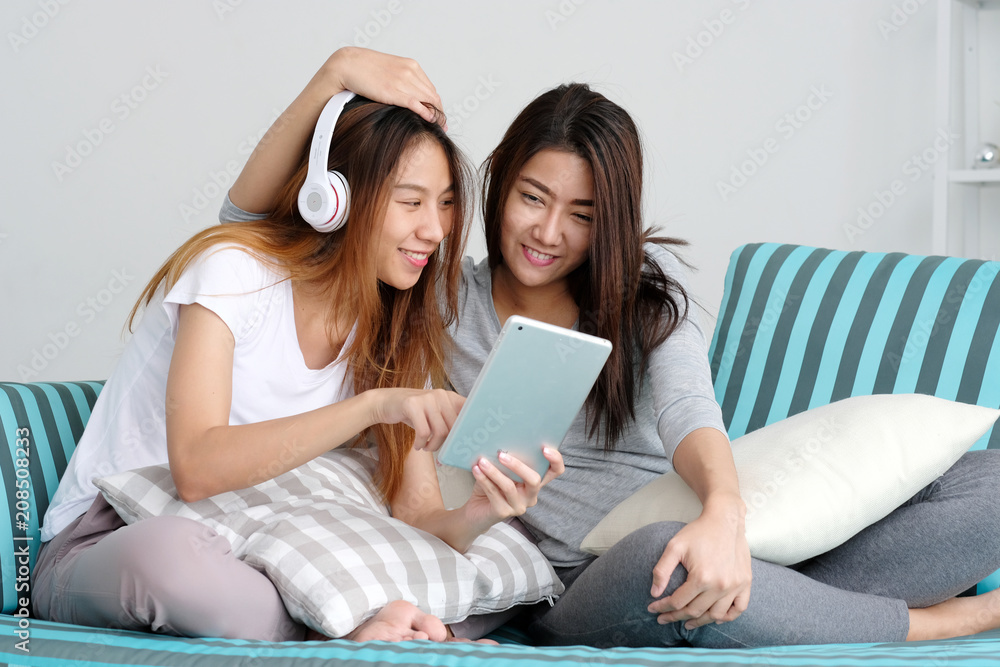 Young cute asia lesbian couple using tablet with happiness at home, lgbt, homosexual, lesbian couple lifestyle Young cute asia lesbian couple using tablet with happiness at home, lgbt, homosexual, lesbian couple lifestyle
