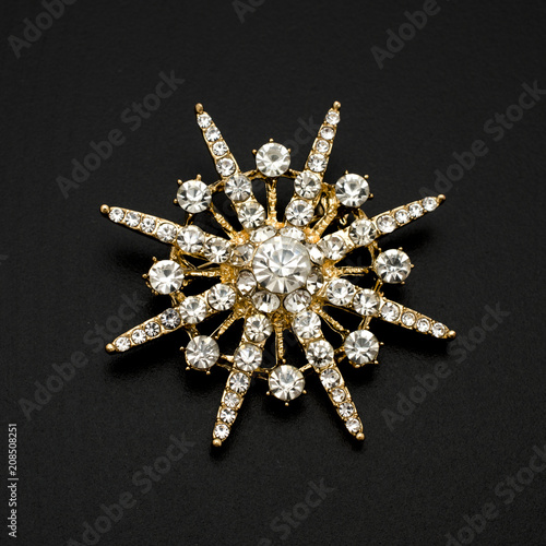 Fotobehang gold round brooch with diamonds isolated on black