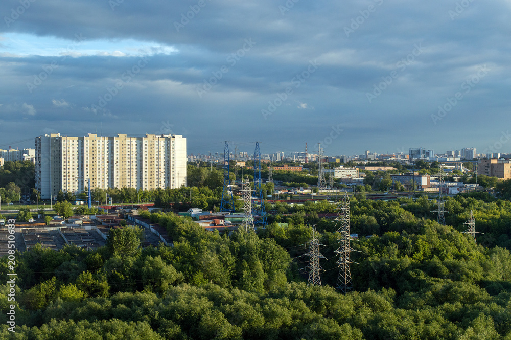 Urban landscape in summer, industrial chimneys and high electricity pylons in big city