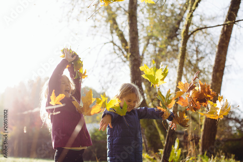 Kids Playing in a Pile of Leaves Smiling in the Autumn Morning Light