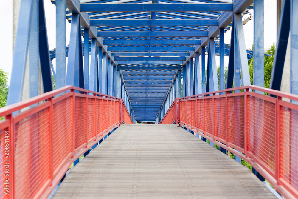 Pedestrian bridge made of wood and steel in red and blue