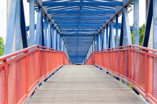 Pedestrian bridge made of wood and steel in red and blue