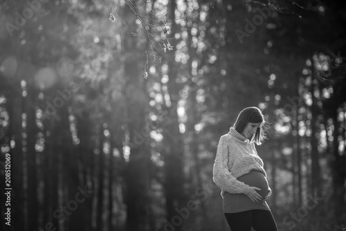 Greyscale image of a pregnant young woman standing outdoors in woodland © Gajus