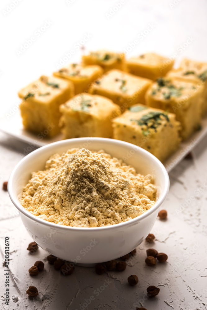 Chick pea flour or Besan powder in a ceramic or wooden bowl along with Gujrati Dhokla snack Chick pea flour or Besan powder in a ceramic or wooden bowl along with Gujrati Dhokla snack