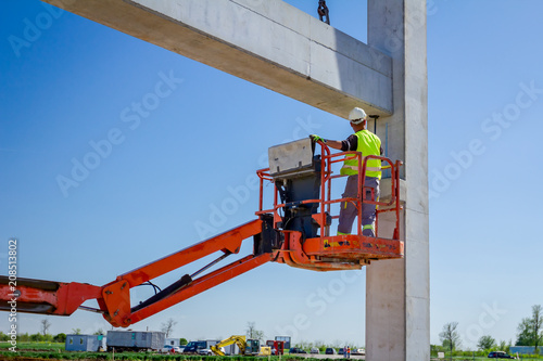 Worker is helping crane from cherry picker, keep balance and direction
