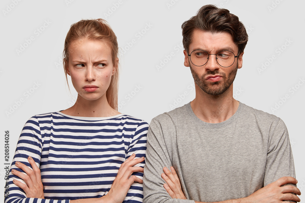 Gloomy female with unhappy expression, keeps hands crossed, looks angrily at boyfriend, have quarrel. Family couple sort out relationship, argue and complain about something. Relationship problem Gloomy female with unhappy expression, keeps hands crossed, looks angrily at boyfriend, have quarrel. Family couple sort out relationship, argue and complain about something. Relationship problem