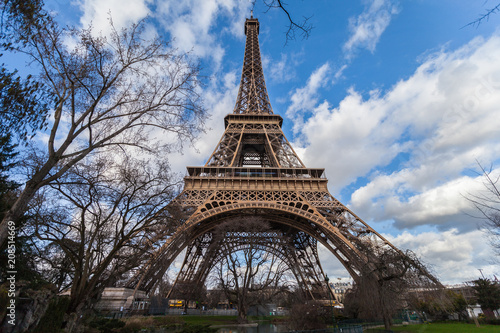 Fototapeta Naklejka Na Ścianę i Meble -  Wide angle view of iconic Eiffel tower with dramatic cloudy blue sky in the background.