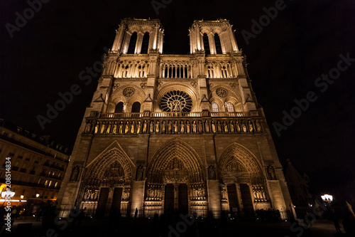 Wide angle view of beautifully illuminatated Notre Dame cathedral in Paris at night.
