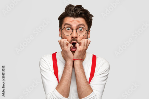 Bild auf Leinwand Portrait of puzzled scared male professor finds out about student`s failure, looks nervously, has trendy hairstyle, wears formal white shirt and red suspenders