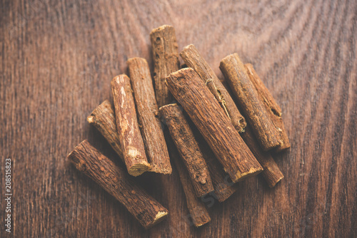 Ayurvedic Mulethi or Liquorice root stick or jeshthamadh powder served in a bowl over moody background photo