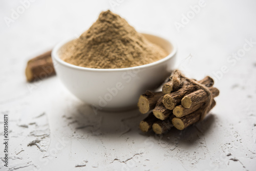 Ayurvedic Mulethi or Liquorice root stick or jeshthamadh powder served in a bowl over moody background photo