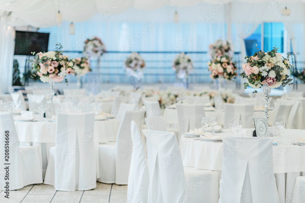 Festive decoration of the wedding celebration in the banquet hall with white tablecloths and flowers Festive decoration of the wedding celebration in the banquet hall with white tablecloths and flowers