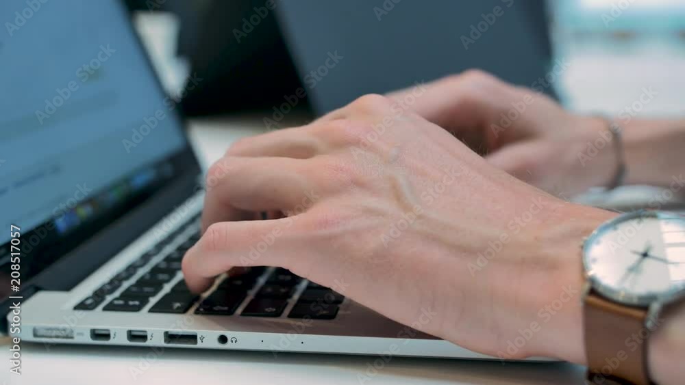 Guy writing and working on a laptop