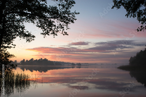 Fototapeta Naklejka Na Ścianę i Meble -  The sun setting over a lake during summertime 
