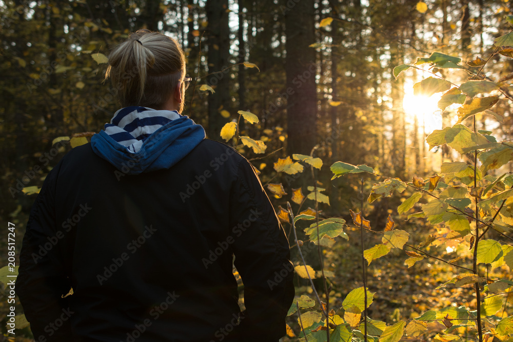 A man in a forest watching the sun set