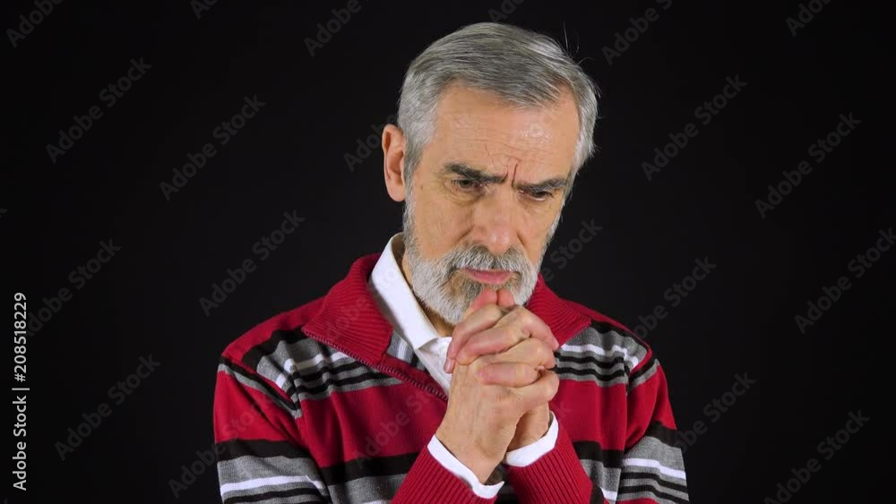 An elderly man prays with hands clasped together - black screen studio An elderly man prays with hands clasped together - black screen studio