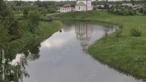 Church on the hill on a background of a cloudy sky and river. Ilyinskaya church in the city of Suzdal near The Kamenka River, Russia. photo