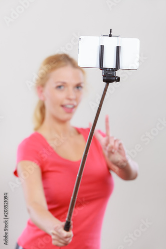 Woman taking picture of herself, phone on stick